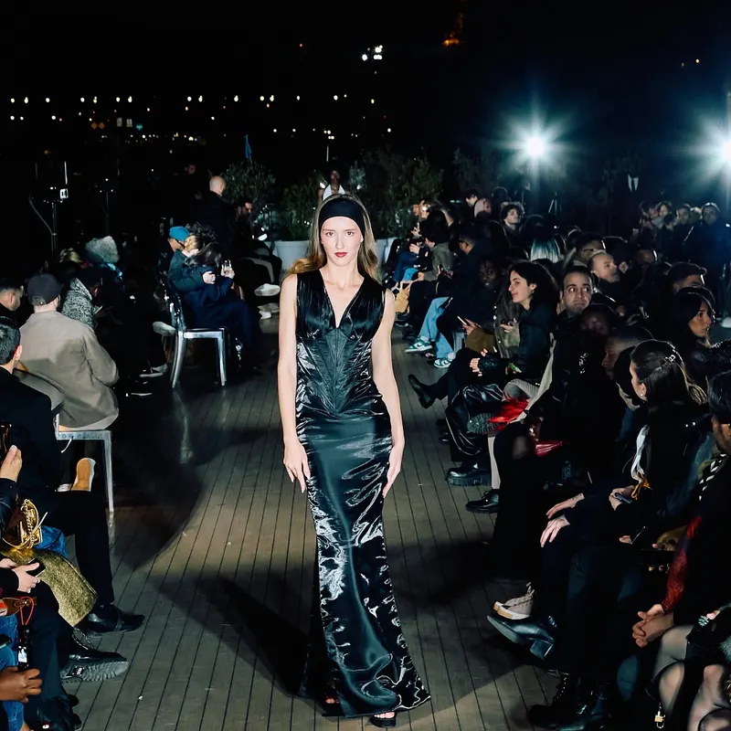 Lisa walking an evening outdoor runway in a dark satin gown