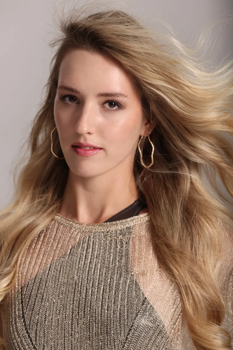 Close portrait of Lisa with windswept hair and gold hoop earrings